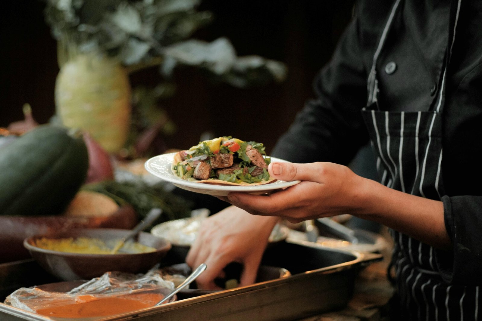 Chef in uniform preparing a fresh salad with vegetables, showcasing culinary artistry.